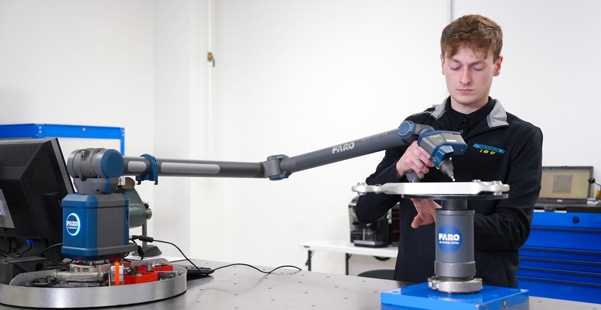 Engineer using a FARO Quantum X arm, fully extended, to measure a part
