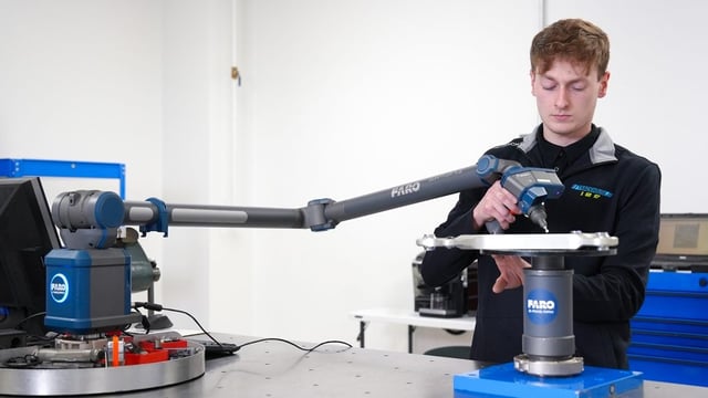 Engineer using a FARO Quantum X arm, fully extended, to measure a part