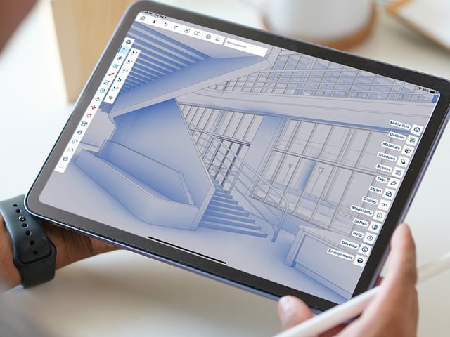 A SketchUp model open on an iPad held in one hand, with a stylus in the other