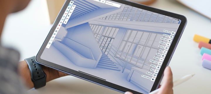 A SketchUp model open on an iPad held in one hand, with a stylus in the other