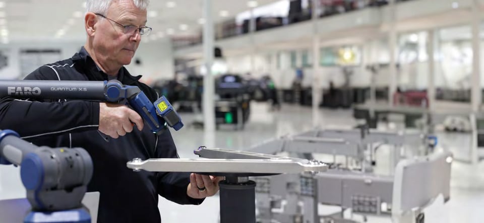 Engineer scanning a suspension control arm with a FARO Quantum X Arm and FAROBlu laser line probe on a production floor