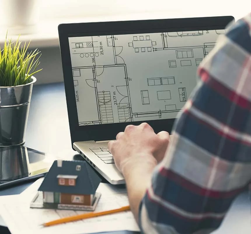 Architectural floor plan displayed on a laptop beside a scale model